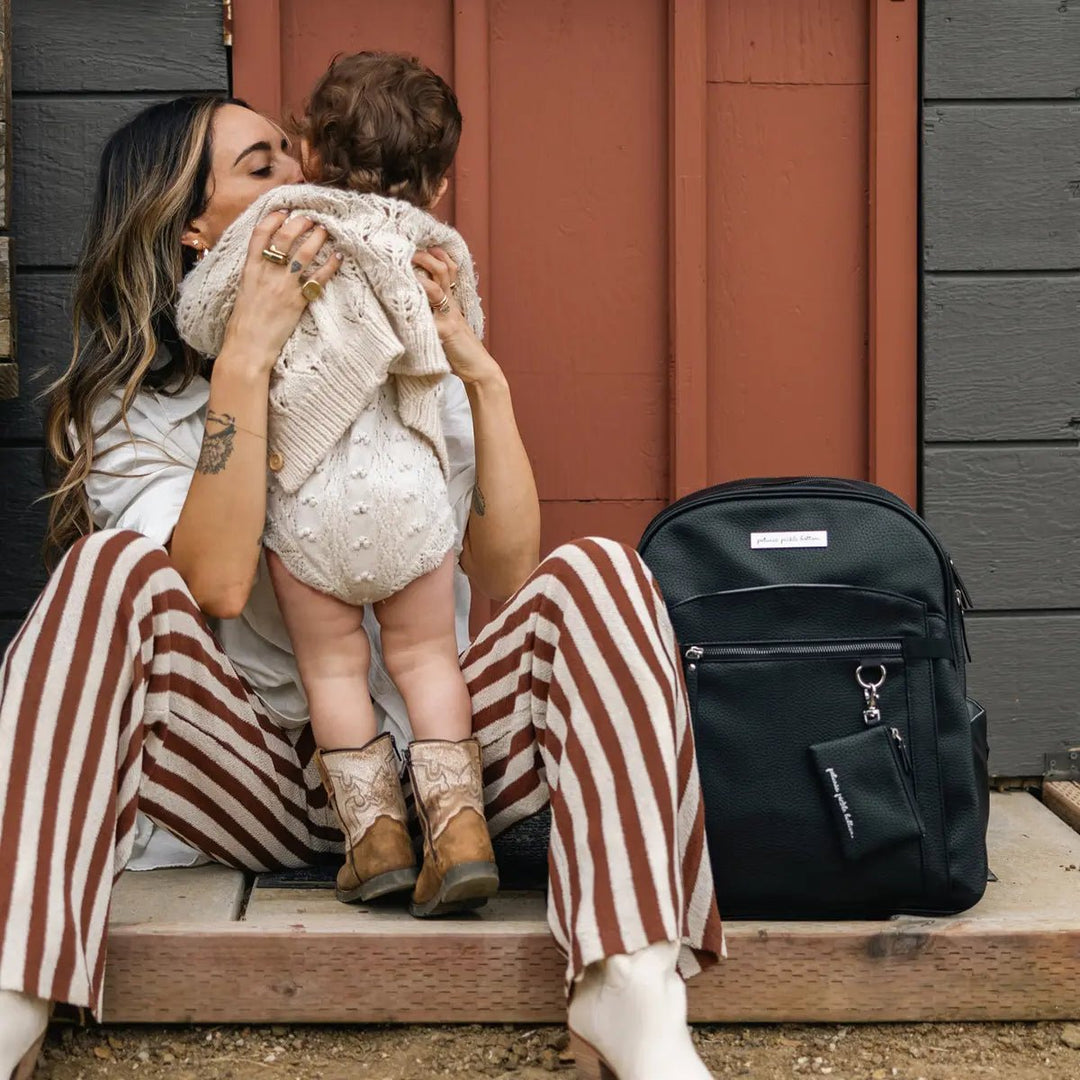 mom wearing the provisions backpack in ebony while holding child