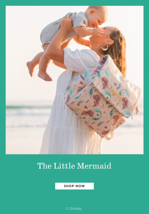 the little mermaid. shop now. by disney. mom wearing the boxy backpack in little mermaid while holding baby
