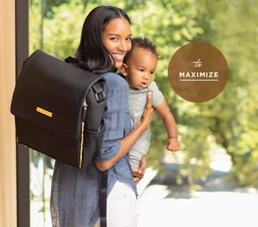 mom holding baby while wearing the boxy backpack in black matte leatherette. to maximize.