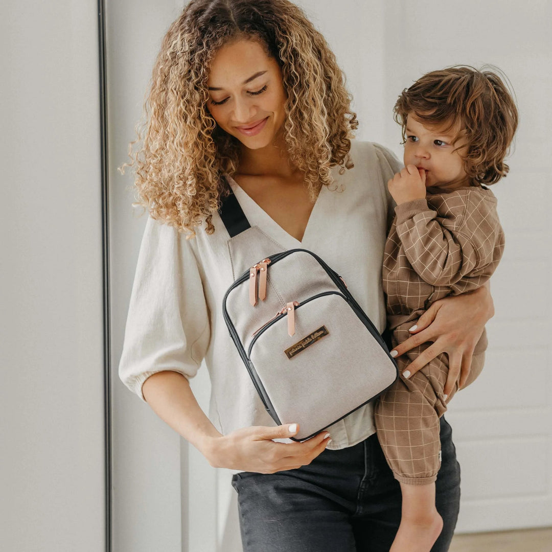 mom wearing Criss-Cross Sling in Black/Sand while holding baby