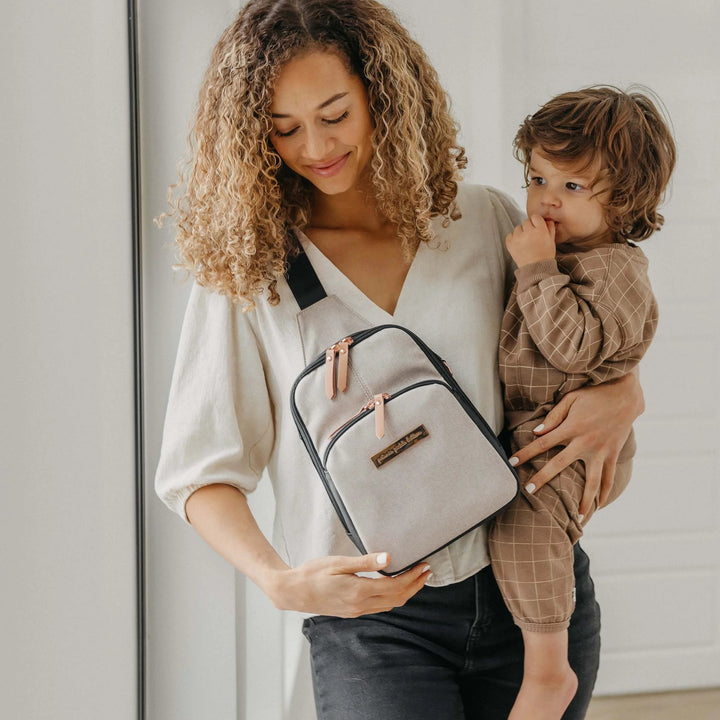 mom wearing Criss-Cross Sling in Black/Sand while holding baby