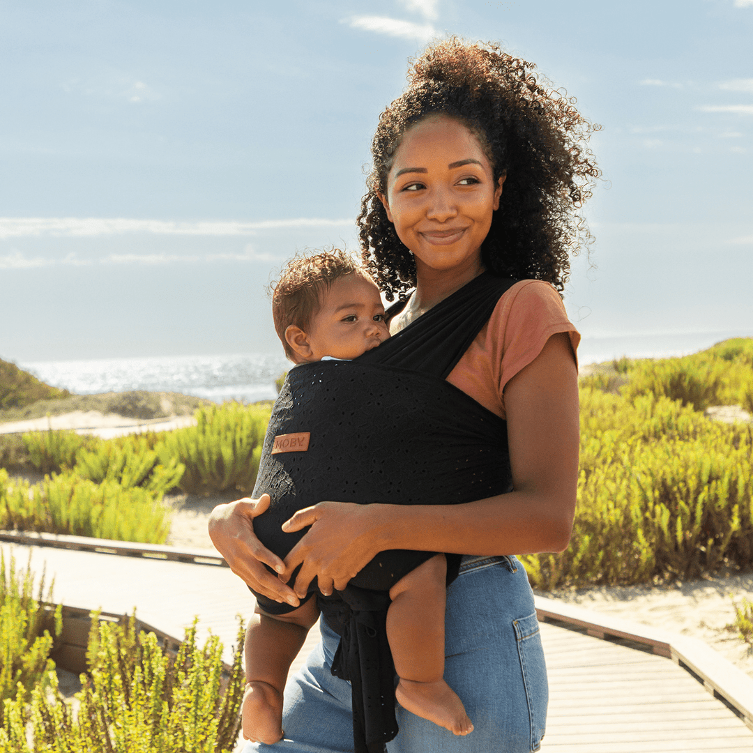 mom wearing baby in Petunia Pickle Bottom x MOBY Easy Wrap Carrier in Black Eyelet