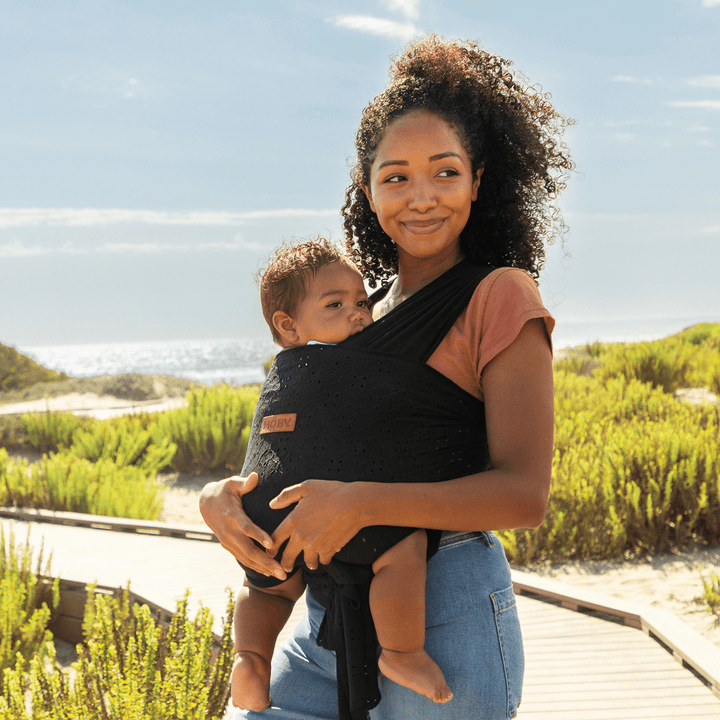 mom wearing baby in Petunia Pickle Bottom x MOBY Easy Wrap Carrier in Black Eyelet