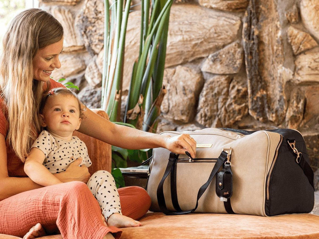 Mom unzipping Weekender Bag with baby daughter sitting in her lap