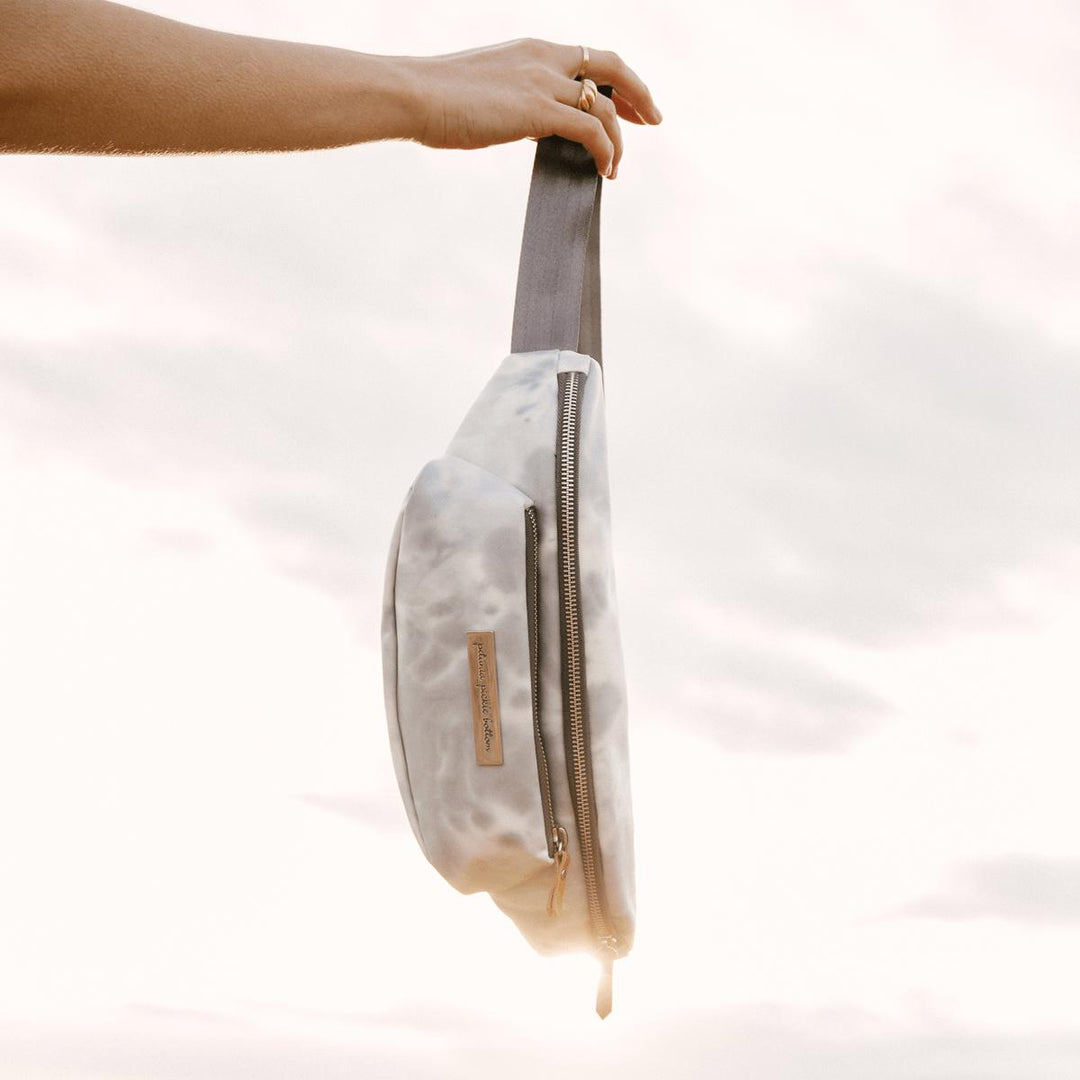 smoke swirl all around belt bag held in bright sunny sky