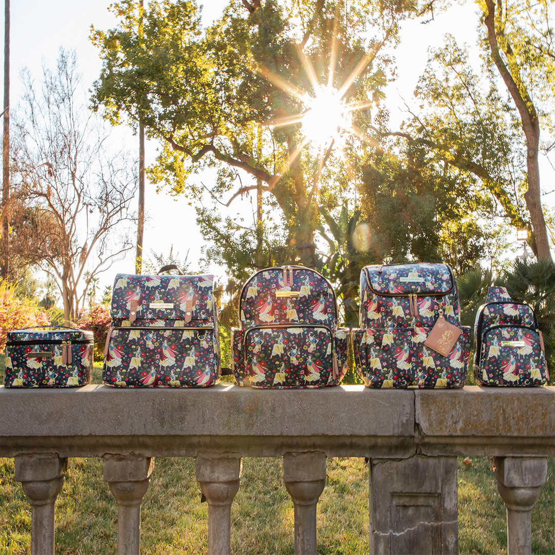 5 products in Snow White's Enchanted Forest collection on a bridge with sun shining through the trees in the background. 