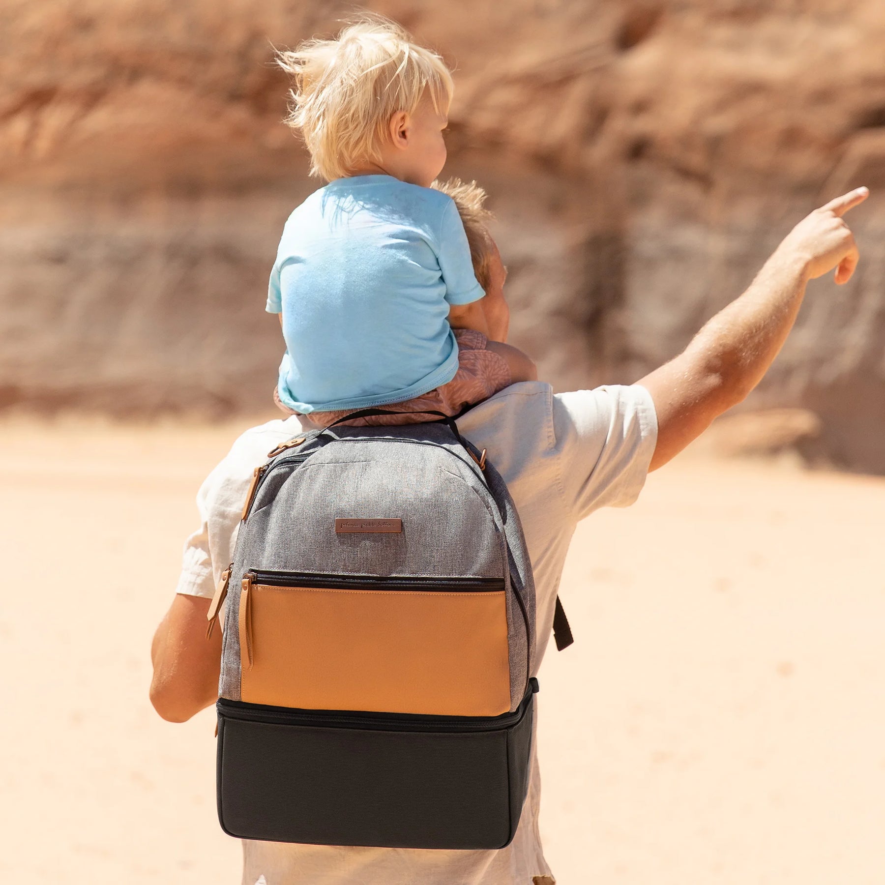 dad wearing axis backpack and graphite camel while holding baby on his shoulders