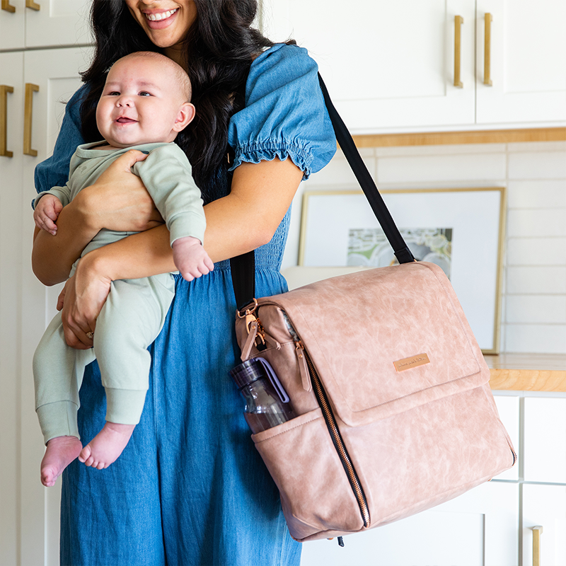 mom holding baby while wearing the boxy backpack in dusty rose