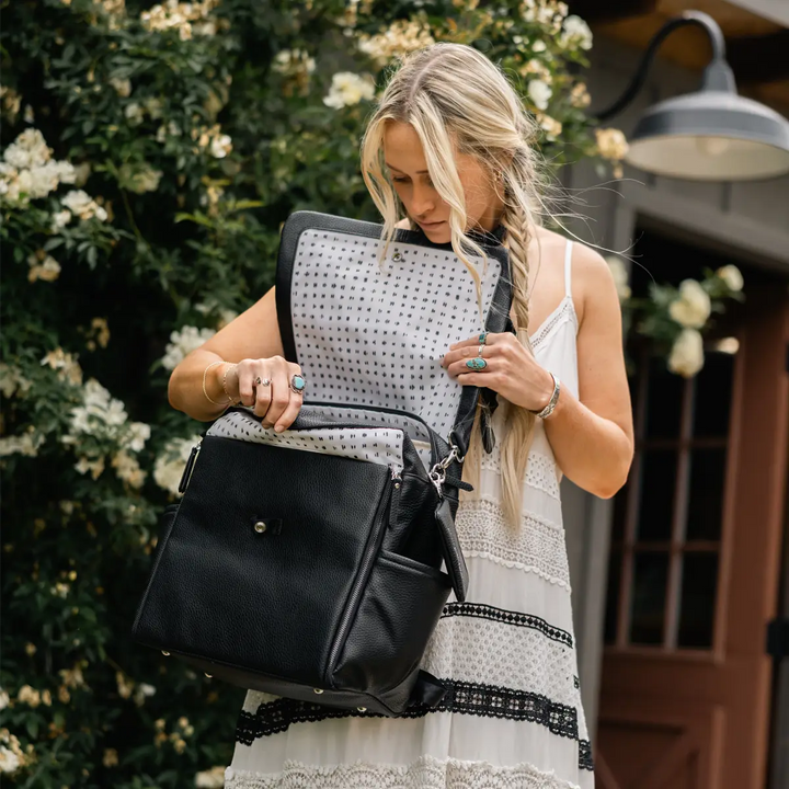 mom wearing the boxy backpack in ebony while opening backpack