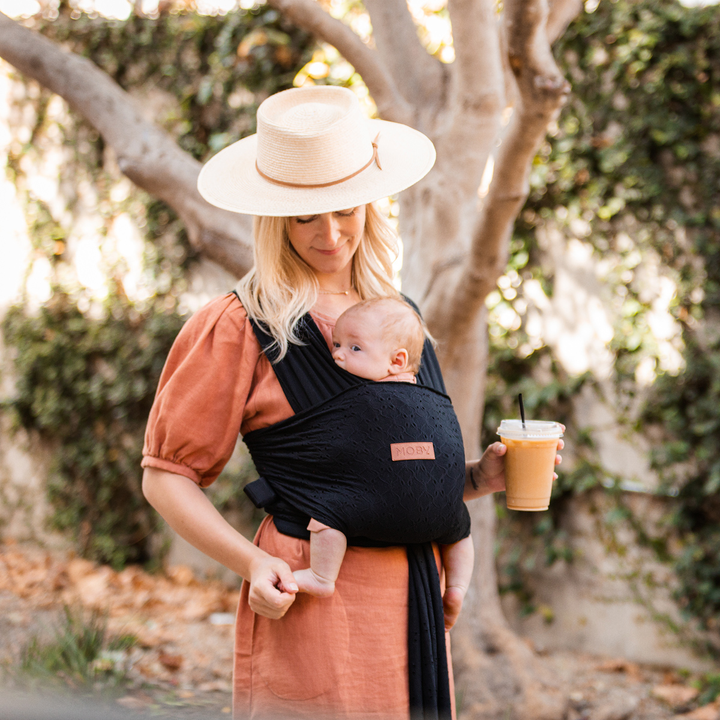 mom wearing baby in Petunia Pickle Bottom x MOBY Easy Wrap Carrier in Black Eyelet