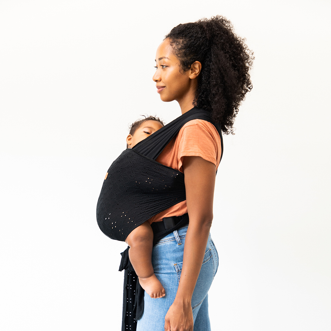 side profile image of mom wearing baby in Petunia Pickle Bottom x MOBY Easy Wrap Carrier in Black Eyelet