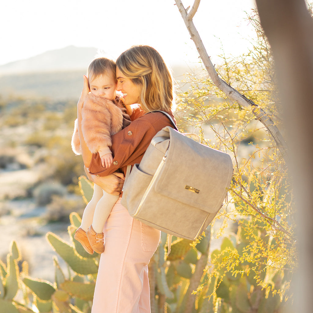 mom wearing boxy backpack in grey matte leatherette while holding baby