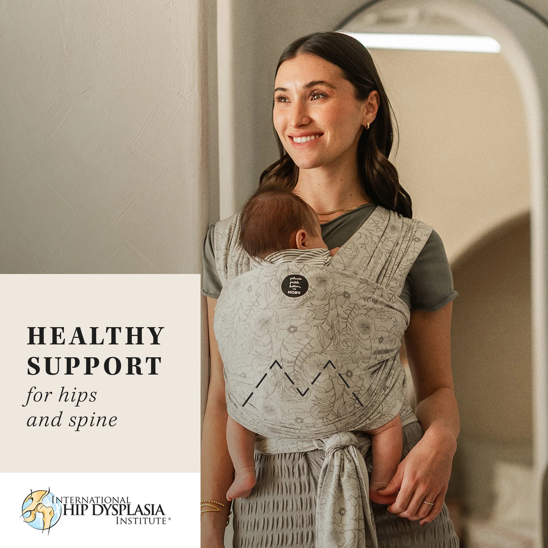 mom wearing baby in Petunia Pickle Bottom x MOBY Classic Wrap in Seaside Poppies. healthy support for hips and spine by international hips dysplasia institute