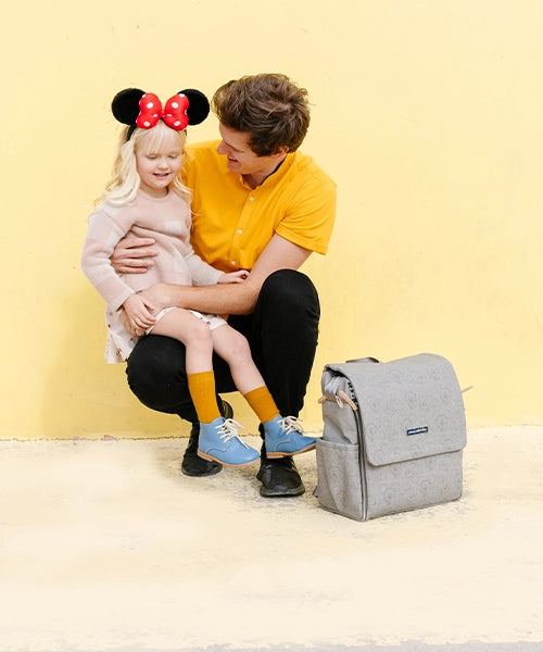 dad sitting girl on his lap with the boxy backpack in love mickey mouse next to him
