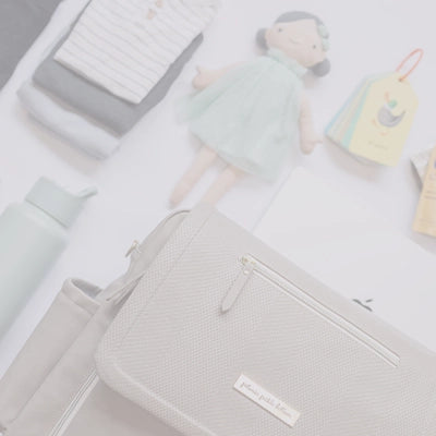 boxy backpack deluxe in sand cable stitch laid out with other items