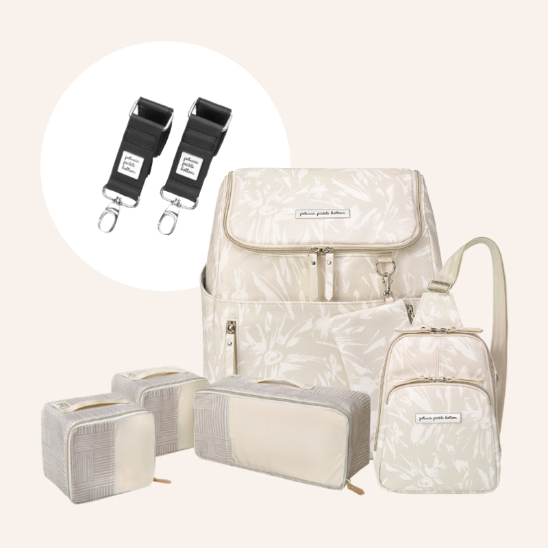 Cream floral diaper bag bundle with matching mini backpack, packing pouches, and black stroller clips on a light background.