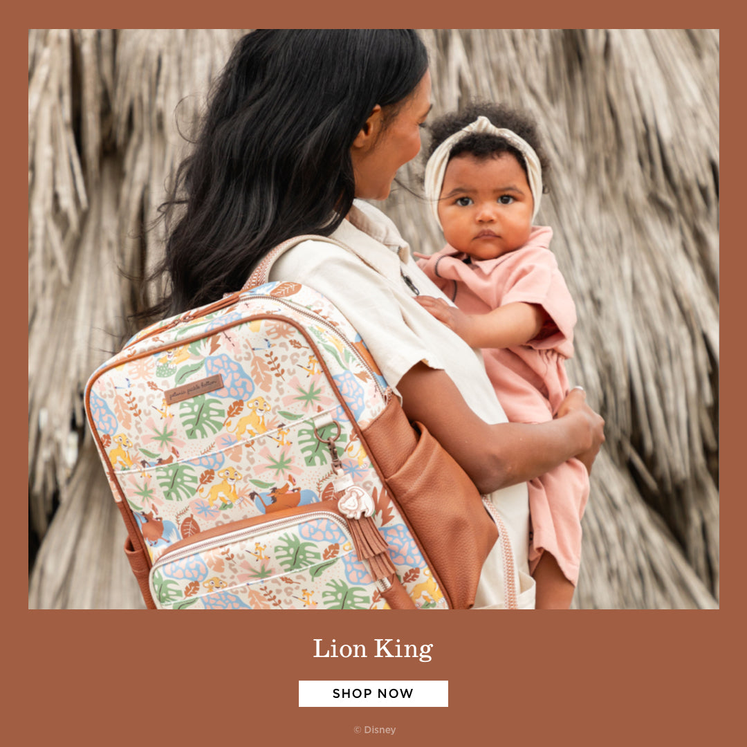 lion king mom holding baby while wearing the sync backpack in hakuna matata