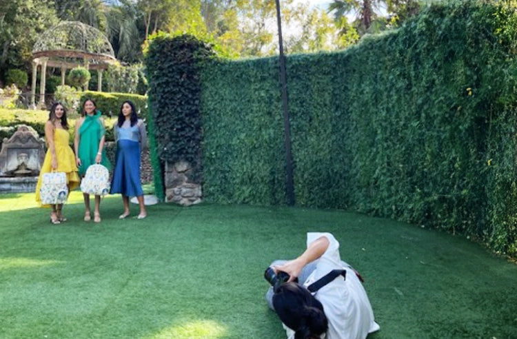 photographer taking pictures of 3 moms on the green grass