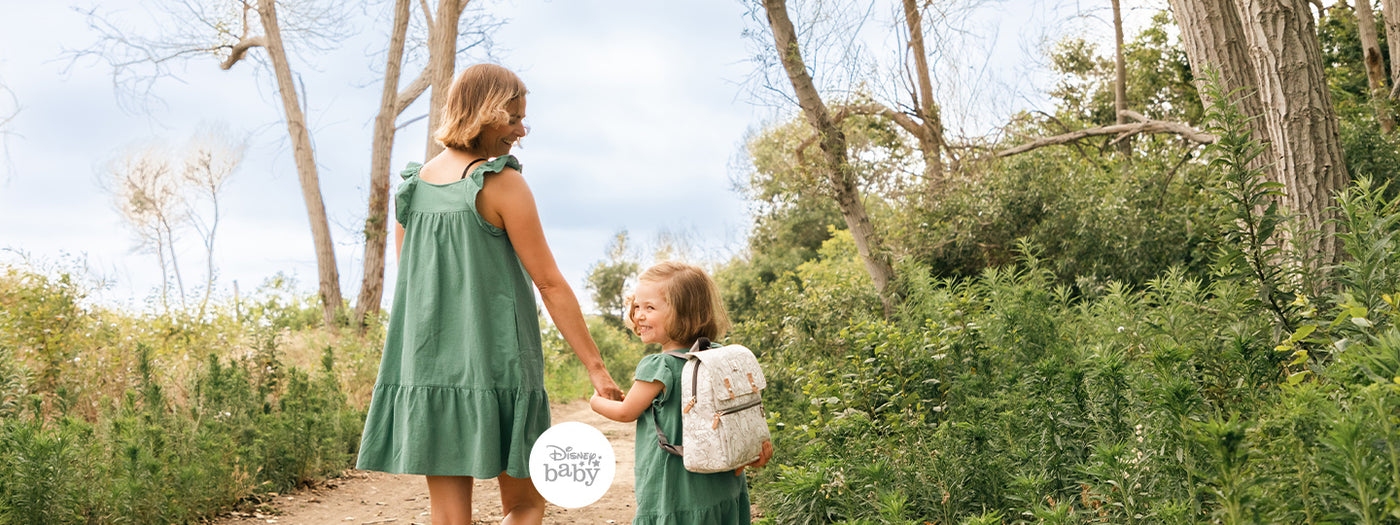 mom and little girl holding hands while little girl is wearing the petunia disney mini backpack in winnie the pooh