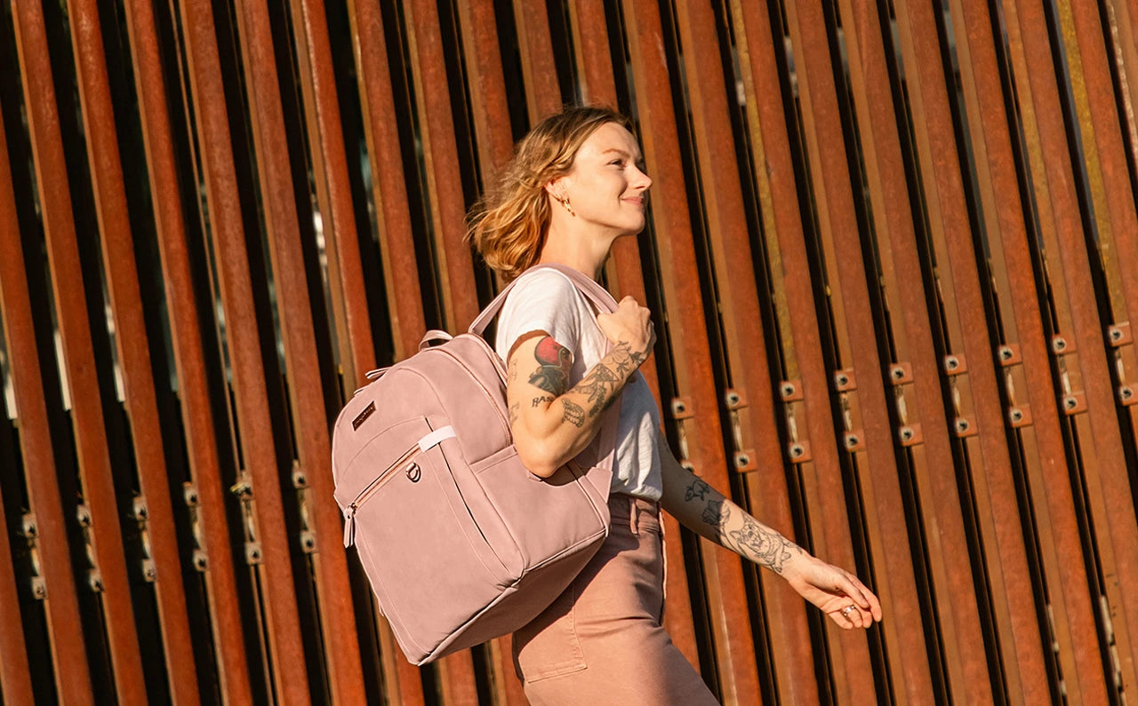 Confident & organized mom walking with Provisions pumping backpack in toffee rose