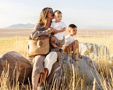 Stylish, modern mother enjoying time with her children outdoors with diaper bag backpack tempo in brioche