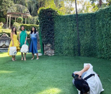 photographer taking pictures of 3 moms on the green grass