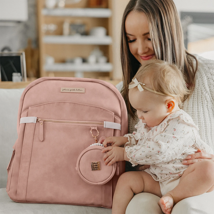 mom hugging baby while baby is playing with petite porter in toffee rose attached to the sync backpack in toffee rose