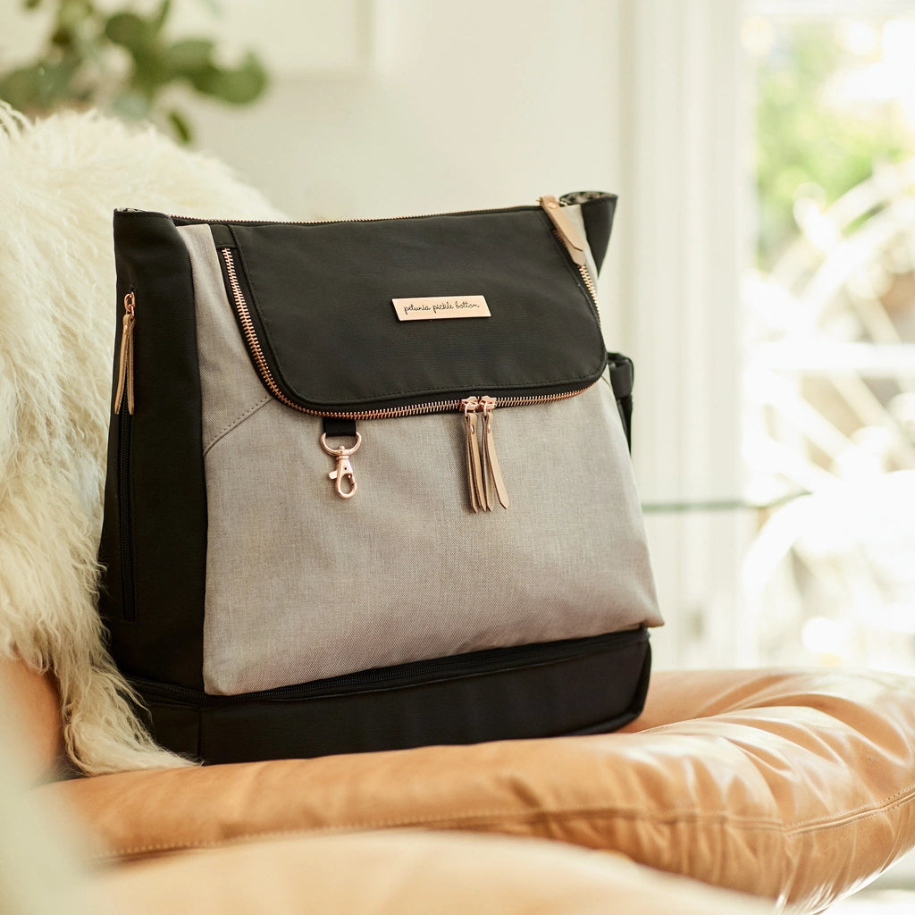 sand colored diaper bag paired with black fabric and accenting rose gold hardware