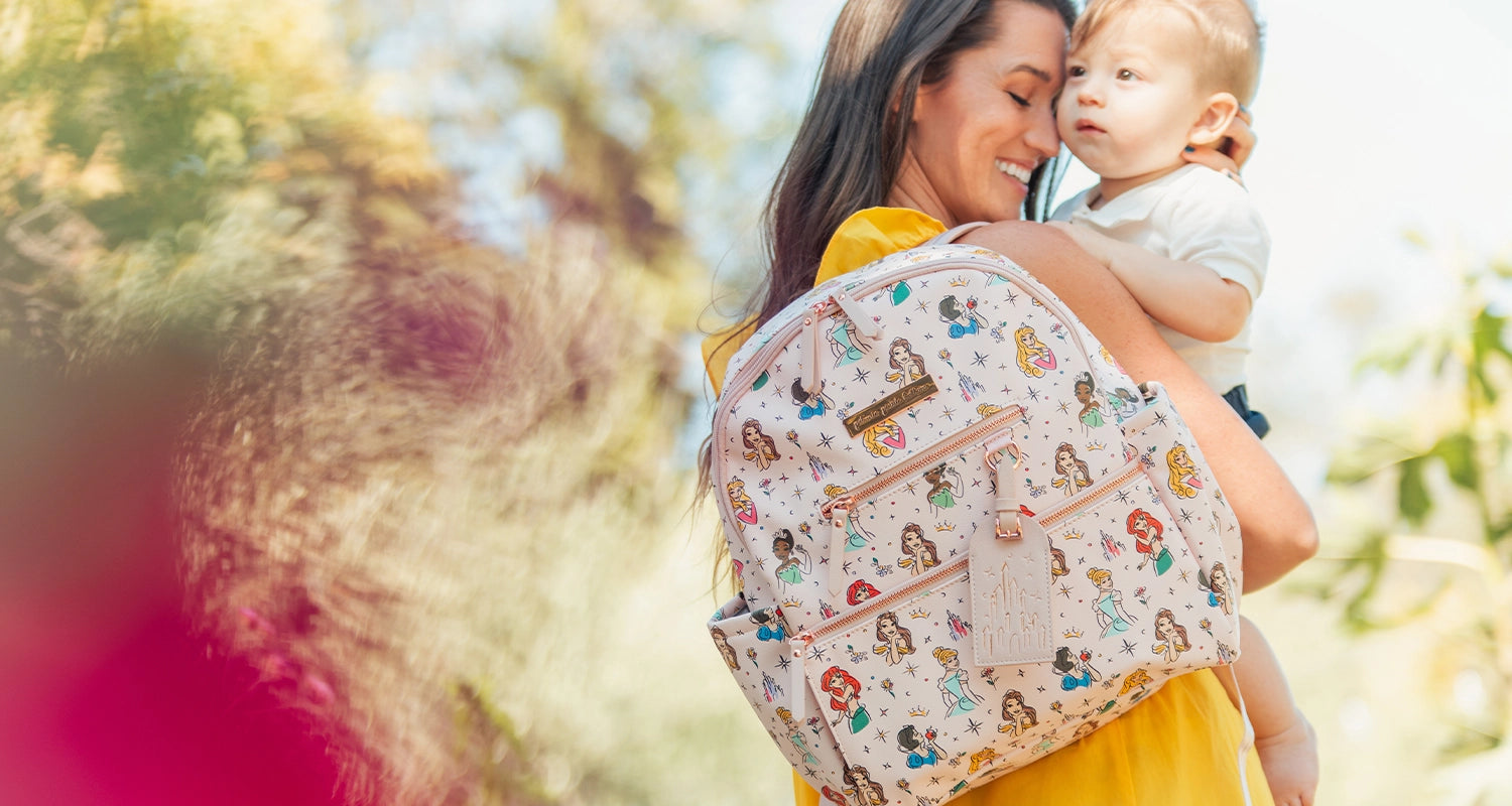 mom holding and hugging baby while wearing the ace backpack in disney princess