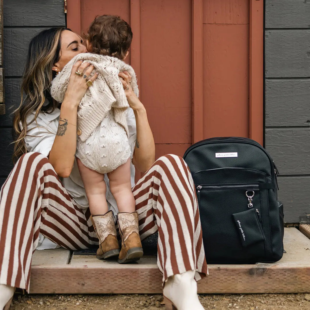 mom wearing the provisions backpack in ebony while holding child