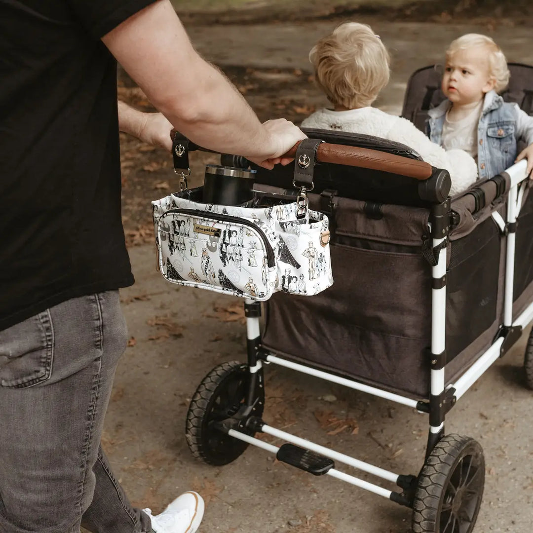 dad pushing cart with 2 kids inside with the wander stroller caddy deluxe and valet stroller clips attached to the cart bar