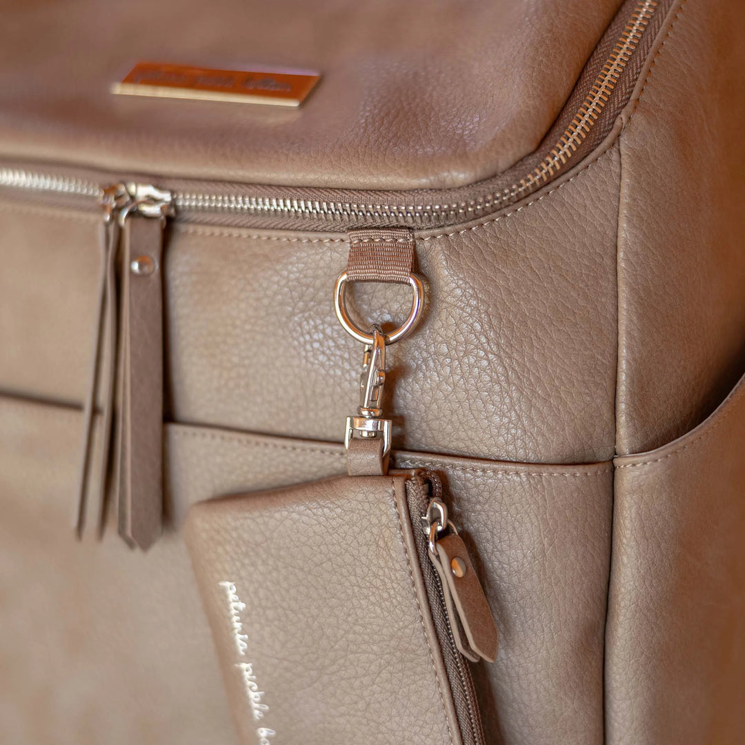 close up image of the d-ring and zippered pouch of the Tempo Backpack in Mink