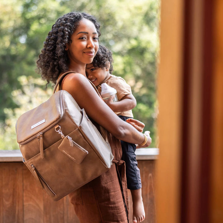 mom holding baby with the Tempo Backpack in Mink over her shoulder