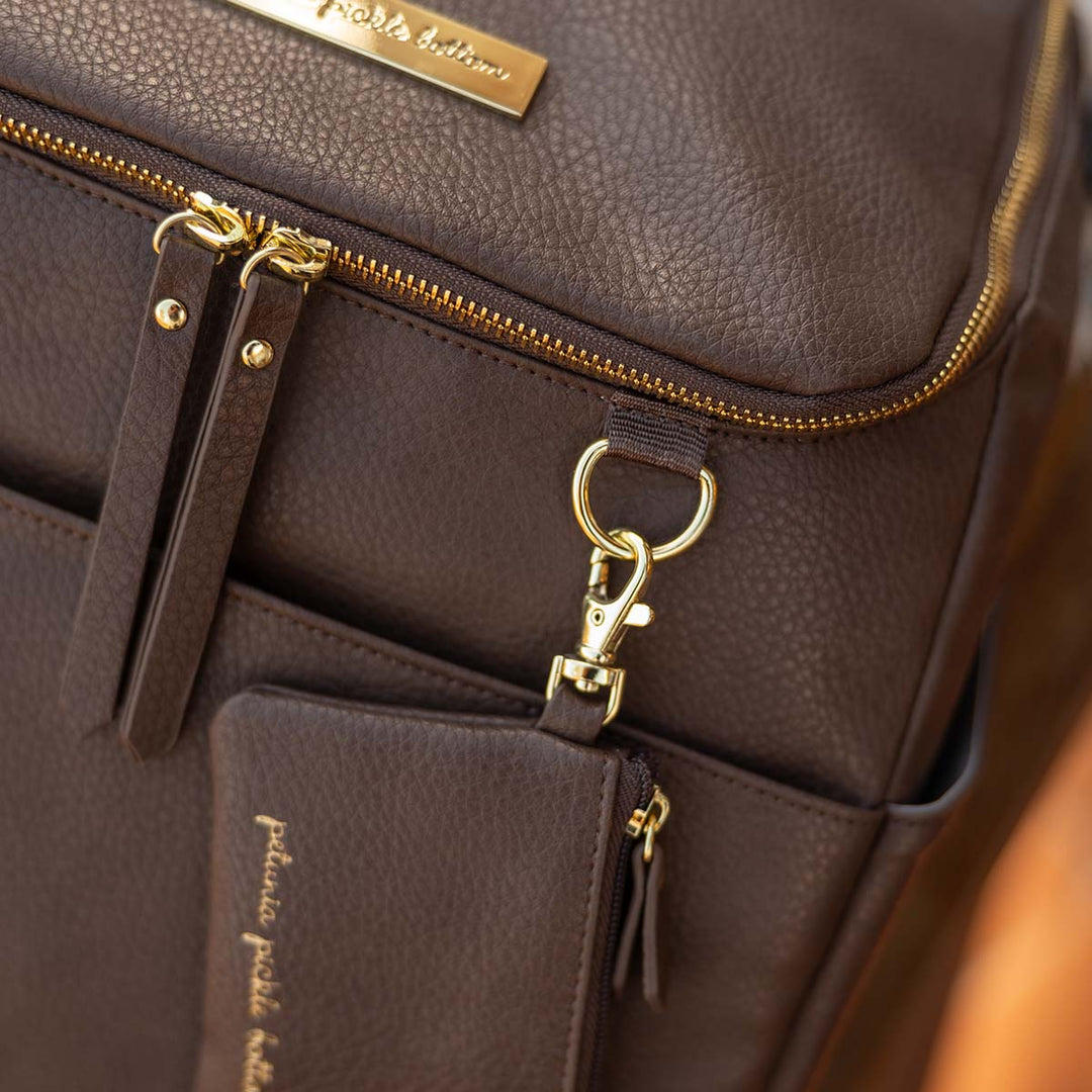 close up image of d-ring and zippered pouch of the Tempo Backpack in Saddle
