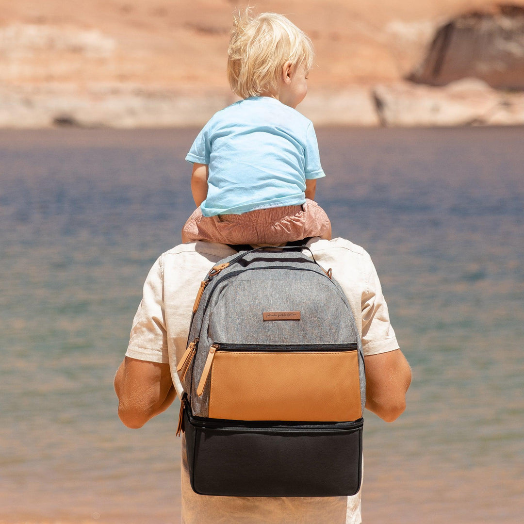 dad carrying baby on his shoulders while wearing the axis backpack in graphite camel