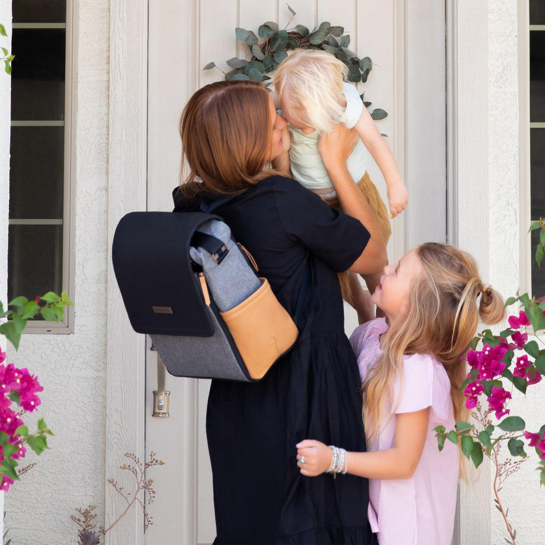 mom playing with kids while wearing the boxy backpack in graphite camel