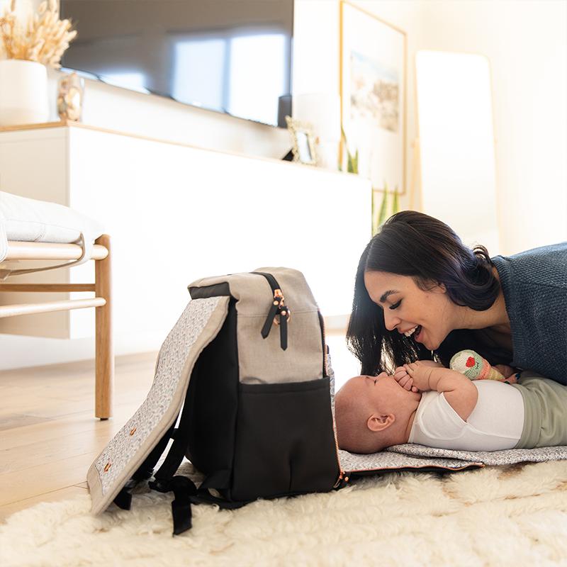 mom playing with baby in front of boxy backpack in black/sand