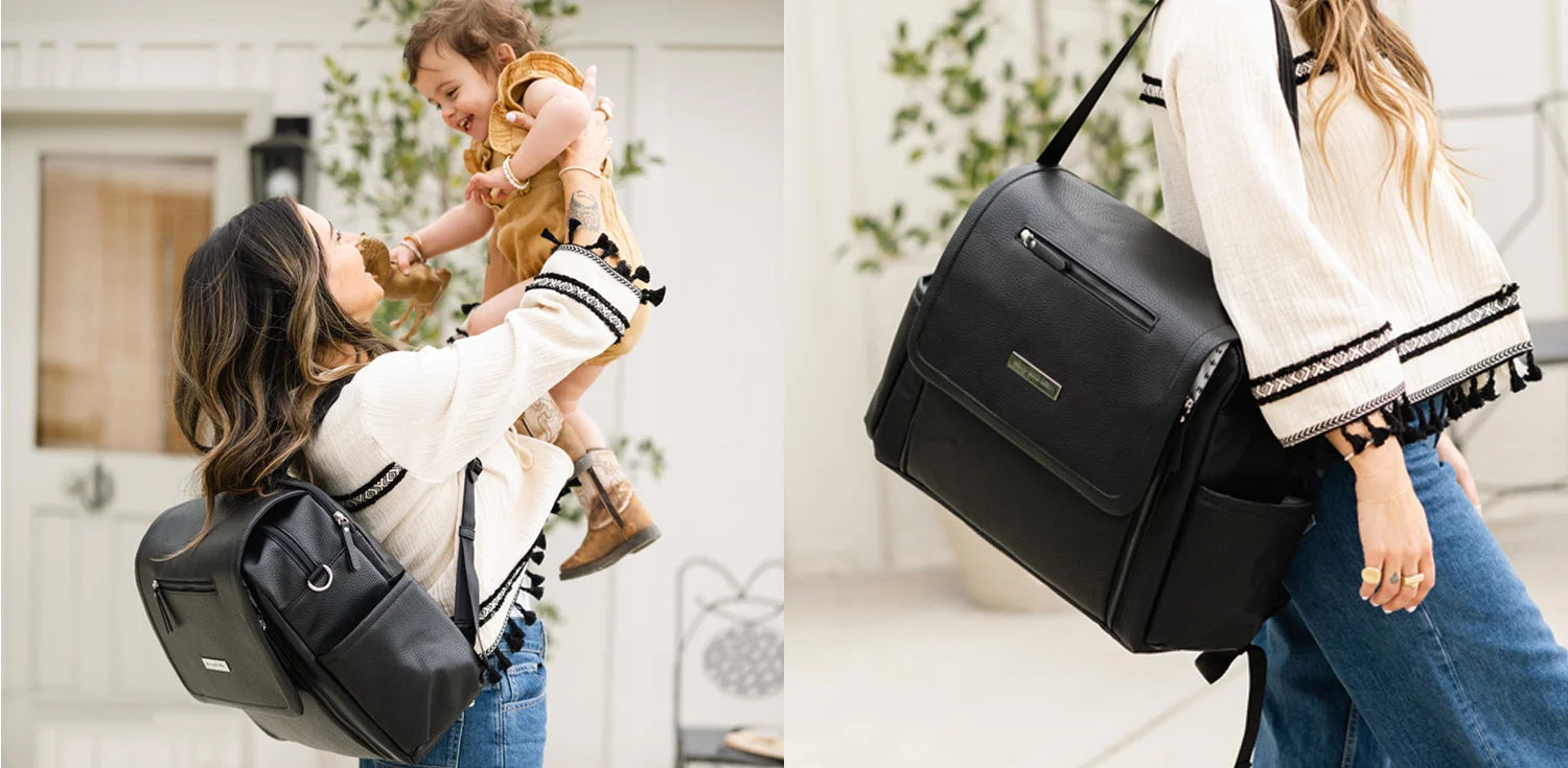 mom holding baby while wearing the boxy backpack deluxe in ebony