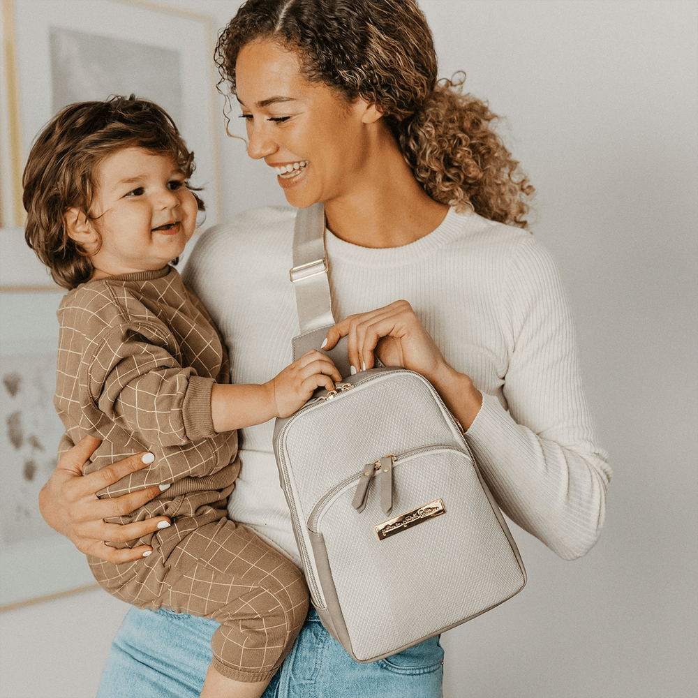 mom holding baby while wearing the Criss-Cross Sling in Grey Matte Cable Stitch