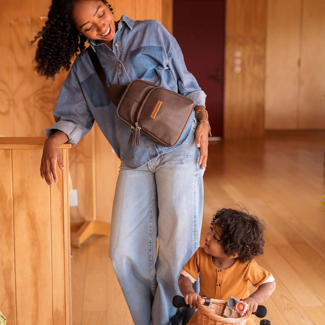 mom wearing the Criss-Cross Sling in Saddle while playing with baby