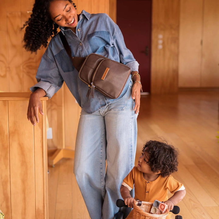 mom wearing the Criss-Cross Sling in Saddle while playing with baby