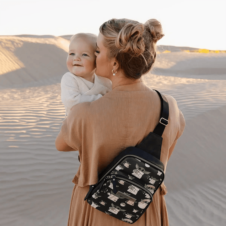 mom wearing the Criss-Cross Sling in The Child while holding and giving a kiss on the cheek to baby