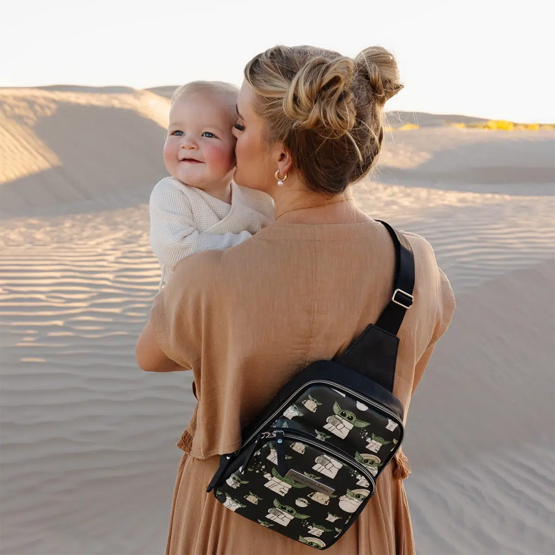 mom holding and kissing baby while wearing the criss-cross sling in the child