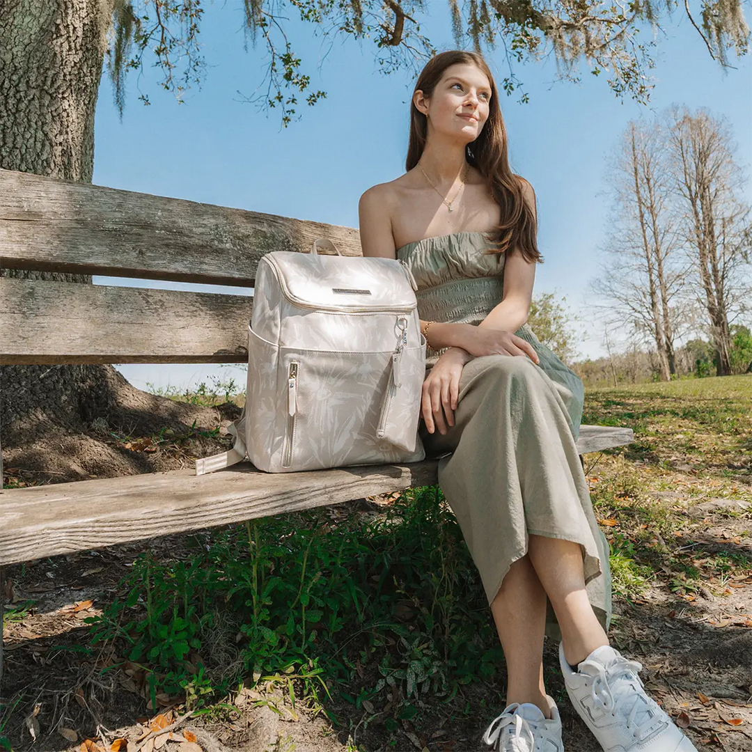 mom sitting on bench with the Tempo Backpack in Linen Blossom