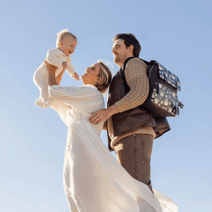 dad wearing the Meta Backpack in The Child while mom is holding baby up in the air