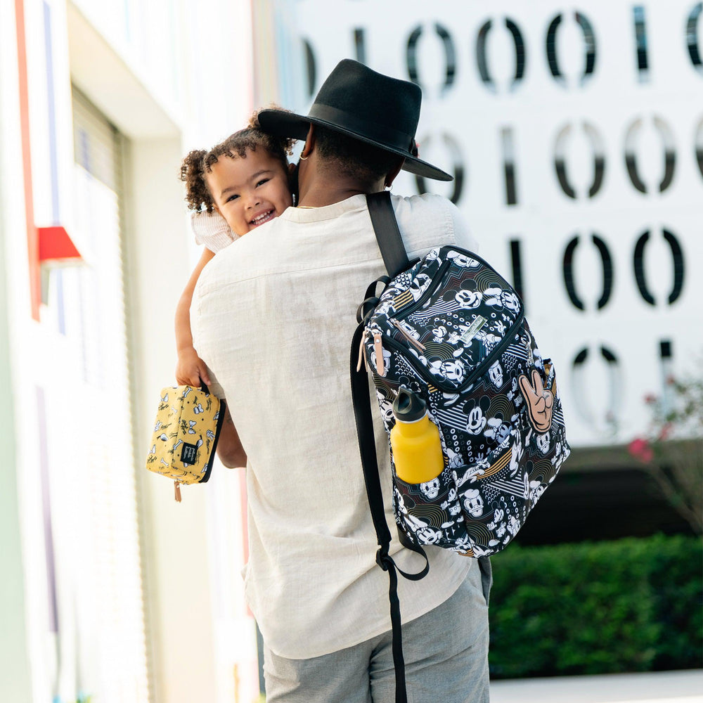 dad holding and hugging baby girl while wearing the method backpack in mickey and friends good times