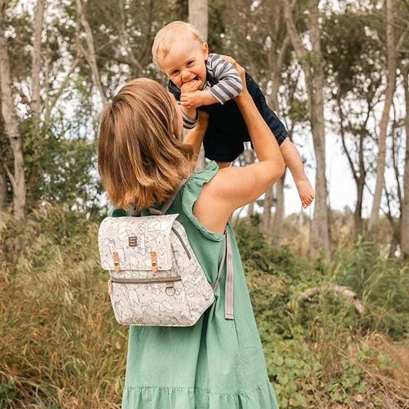 mom holding baby in air while wearing the mini meta backpack in playful pooh