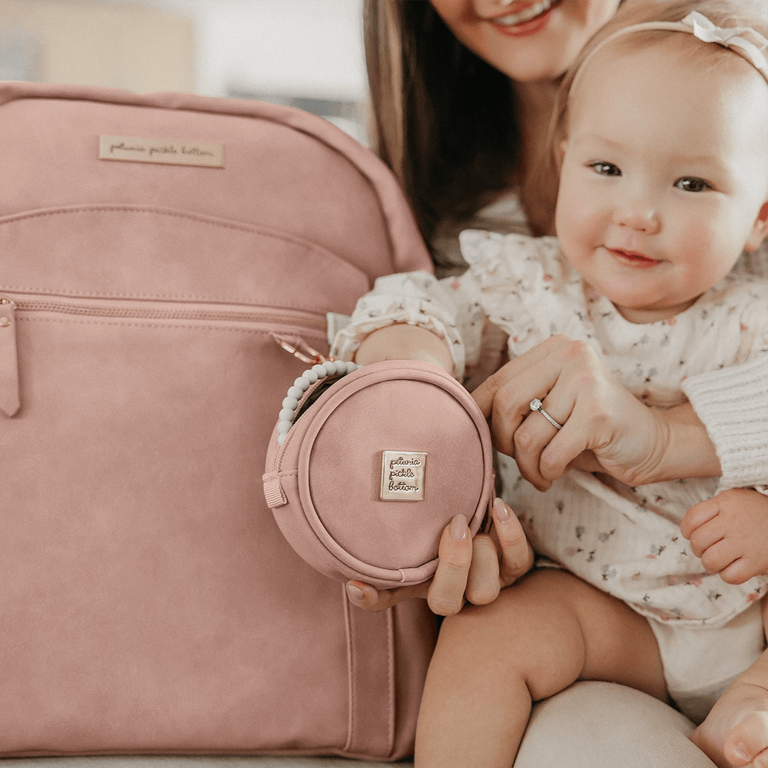 mom hugging baby while baby is playing with petite porter in toffee rose attached to the sync backpack in toffee rose