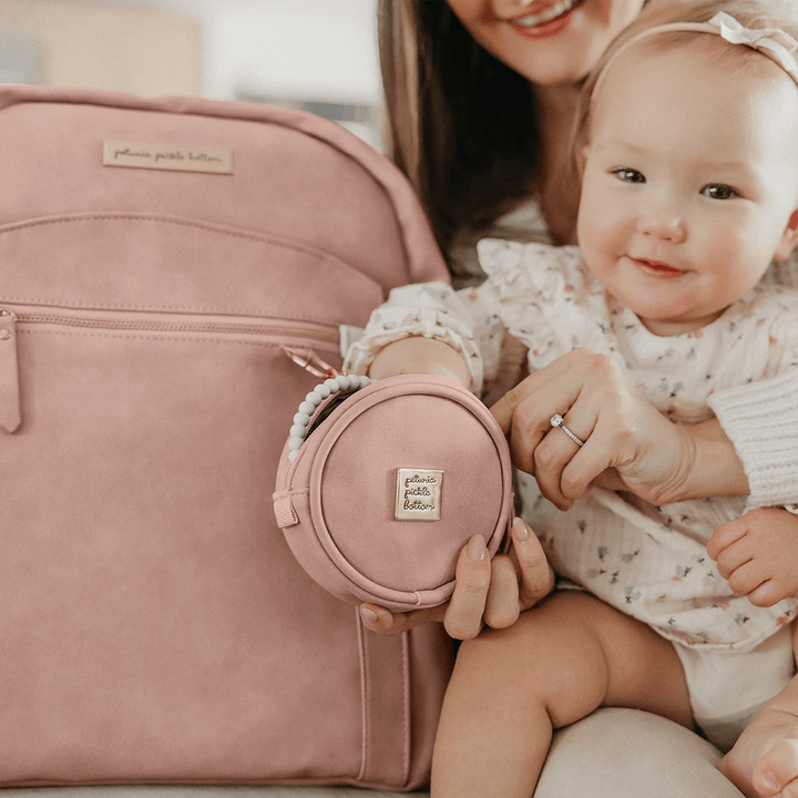 mom hugging baby while baby is playing with petite porter in toffee rose attached to the sync backpack in toffee rose