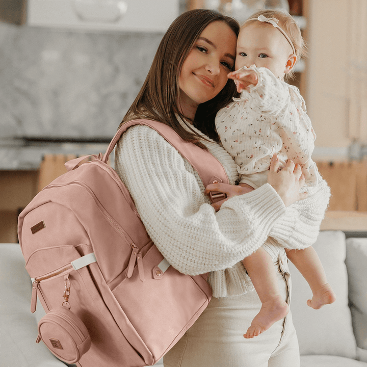 mom hugging baby while wearing the provisions backpack in toffee rose with petite porter attached to the backpack